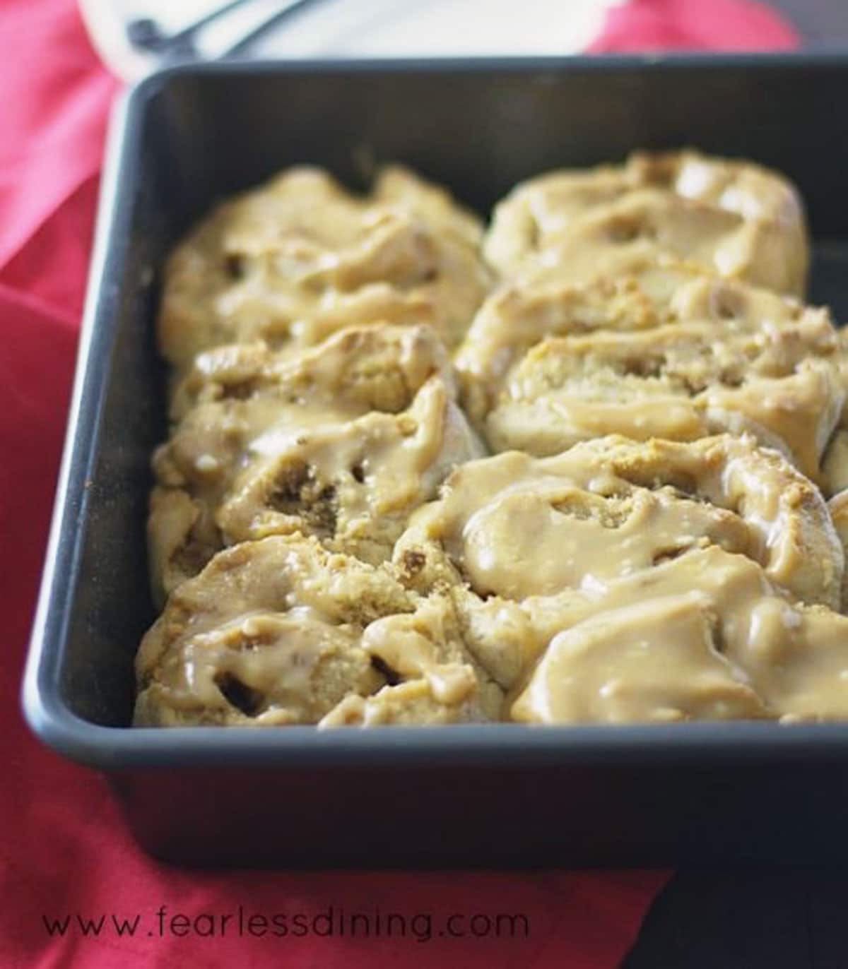 A pan of cooked peanut butter glazed cinnamon rolls.