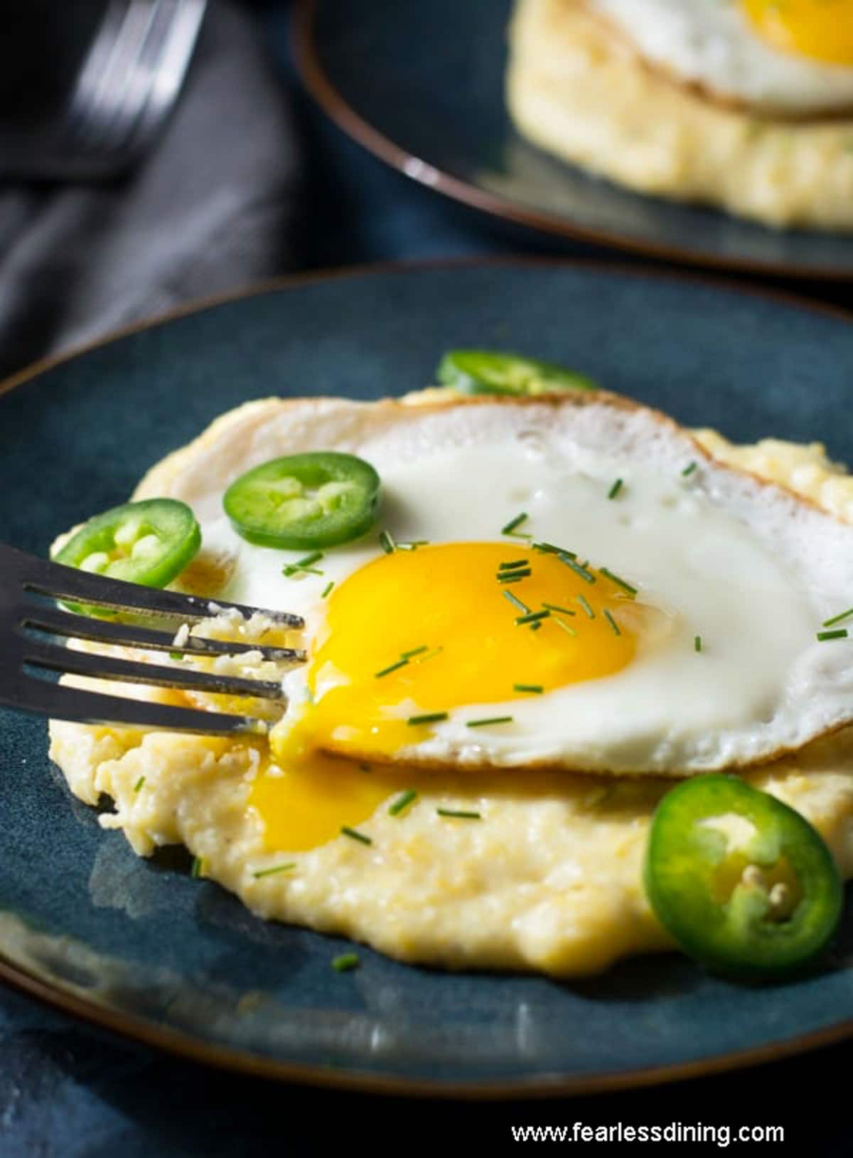 A fork breaking the yellow runny middle on a sunny side up egg.