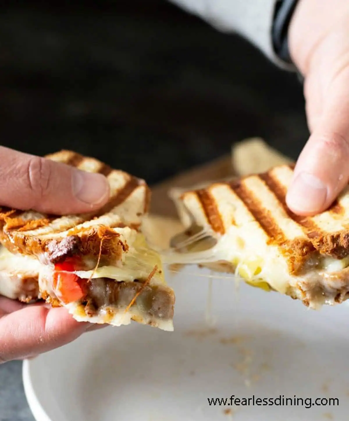 holding a panini with stretching melted cheese