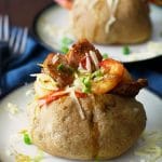 Two jambalaya stuffed baked potatoes on plates.