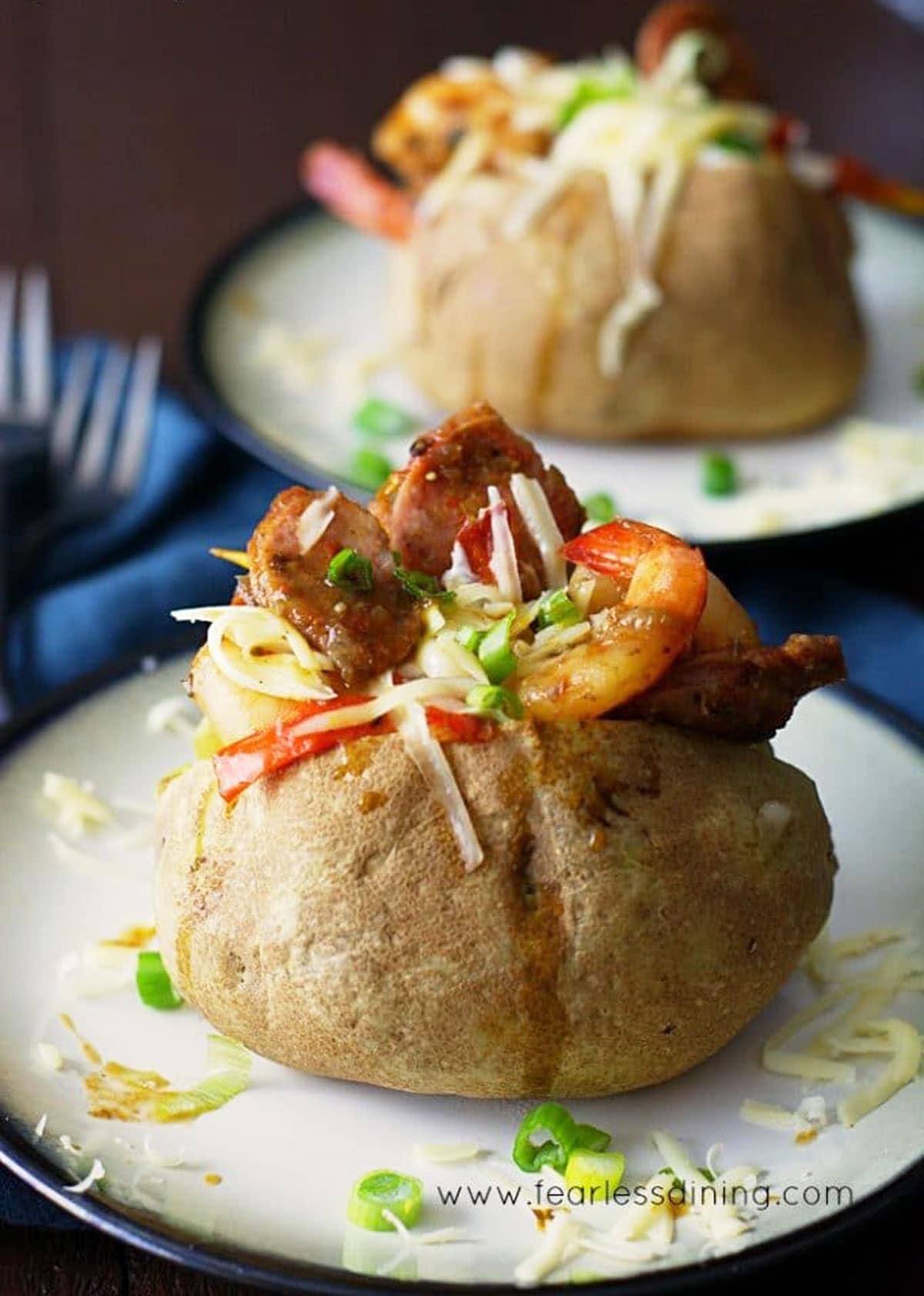 Two jambalaya stuffed baked potatoes on plates.