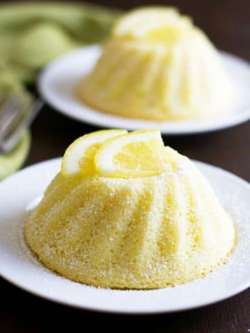 Two lemon yogurt cakes on little white plates.
