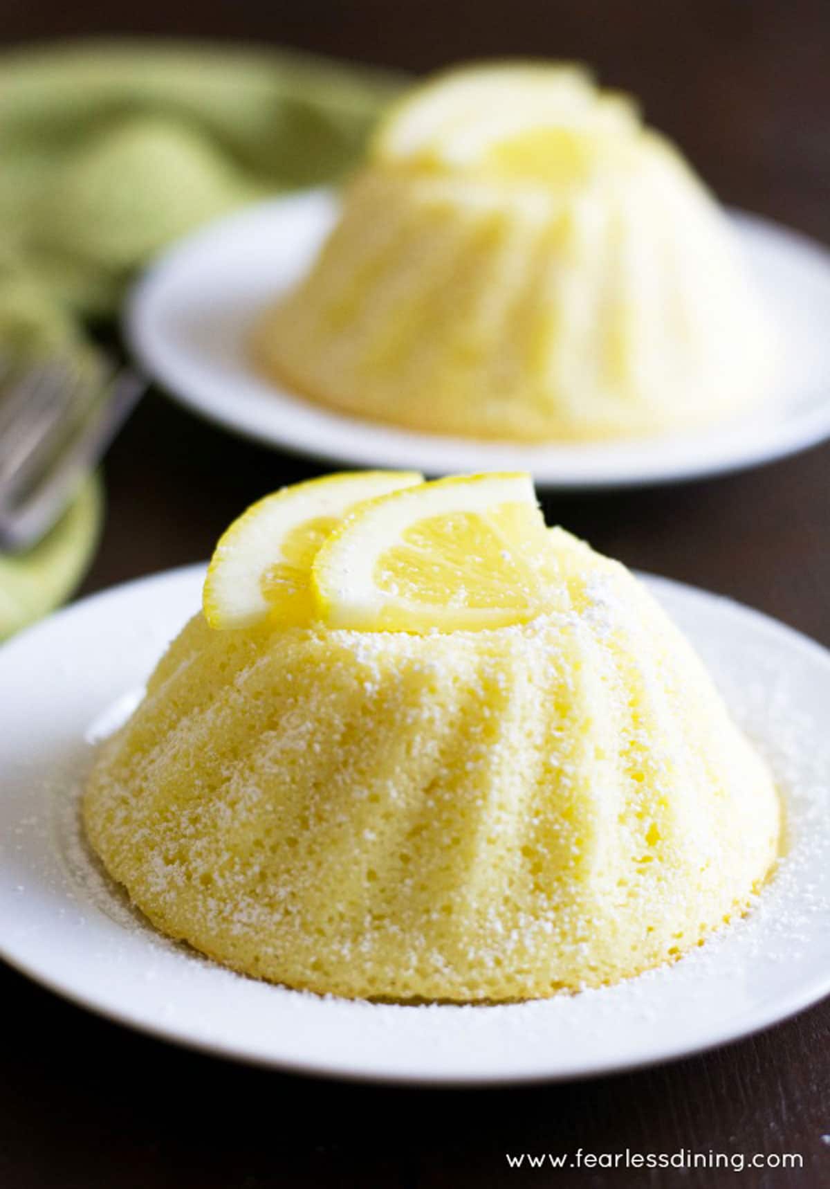 Two lemon yogurt cakes on little white plates.