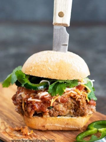 a meatloaf burger on a cutting board with a knife stabbing into it
