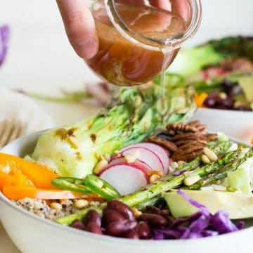 Pouring dressing over the buddha bowl.