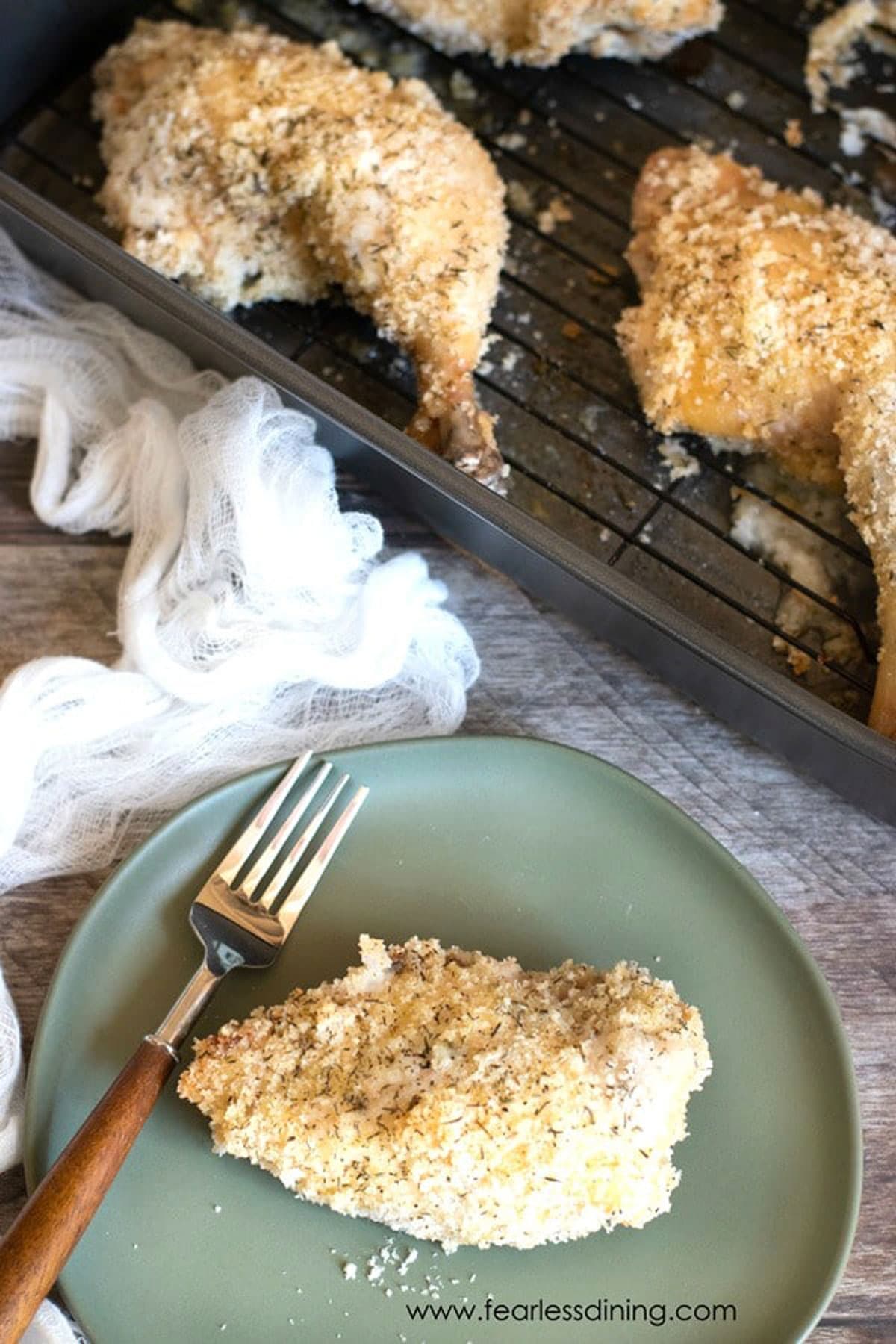 A piece of oven fried chicken on a pale green colored plate.