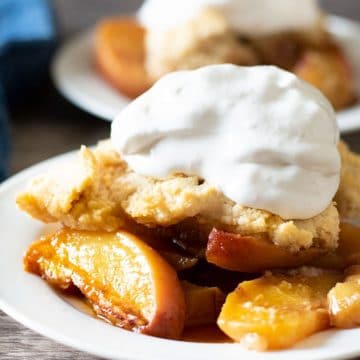 A serving of peach cobbler topped with whipped cream.