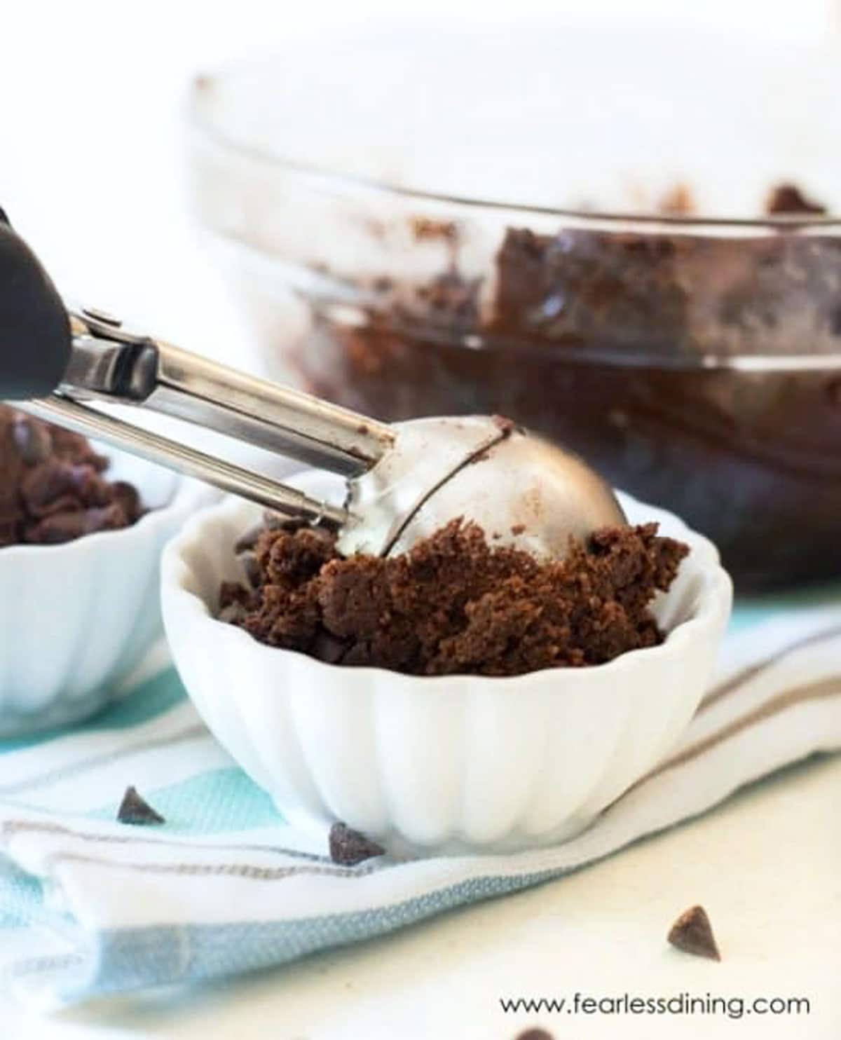 Dropping a scoop of chocolate cookie dough into a bowl.