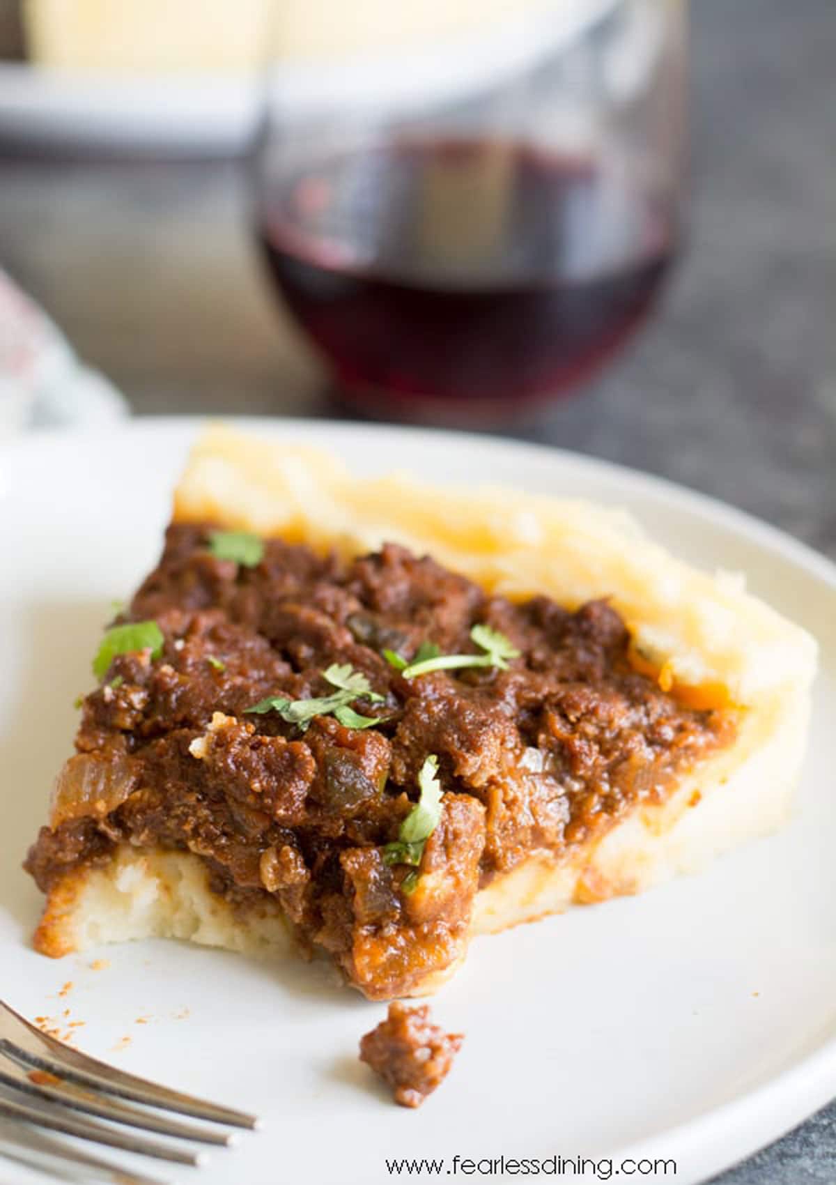 A slice of sloppy joe pie with  piece cut out with a fork.