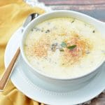 A bowl of oyster chowder next to a yellow napkin.