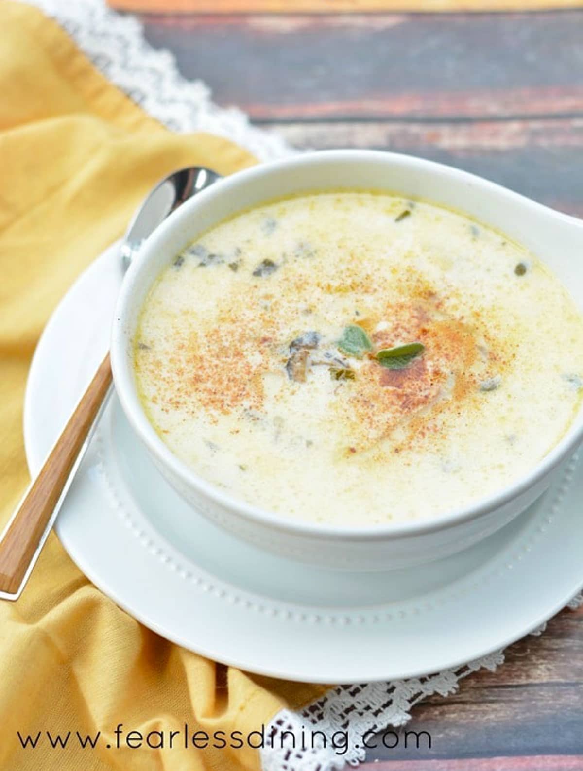 A bowl of oyster chowder next to a yellow napkin.