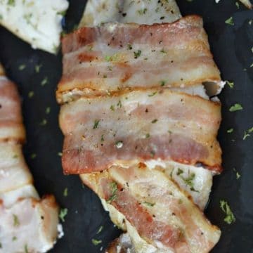 cooked tilapia wrapped in bacon on a baking sheet
