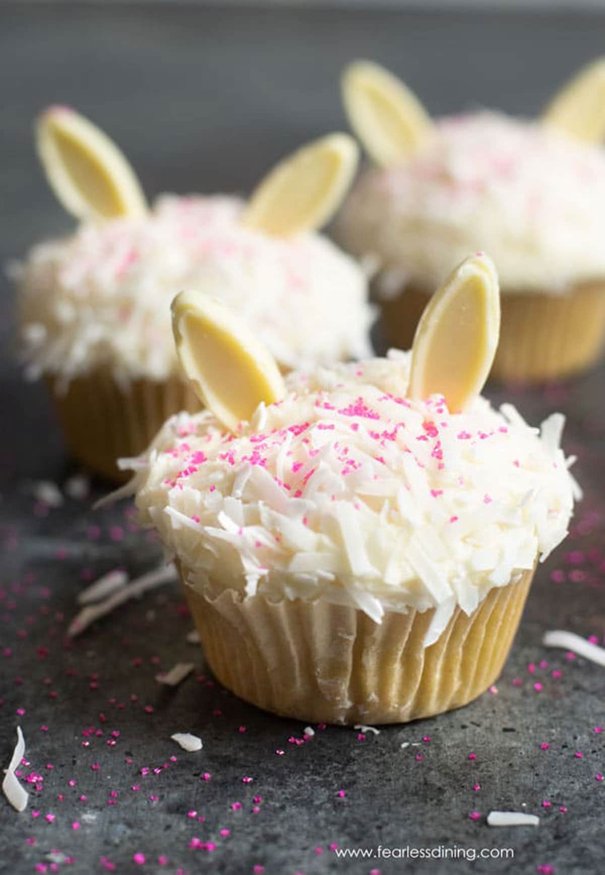 The coconut cupcakes decorated with white chocolate bunny ears for Easter.