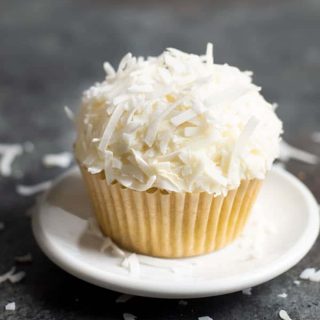 A single coconut cupcake on a small white plate.