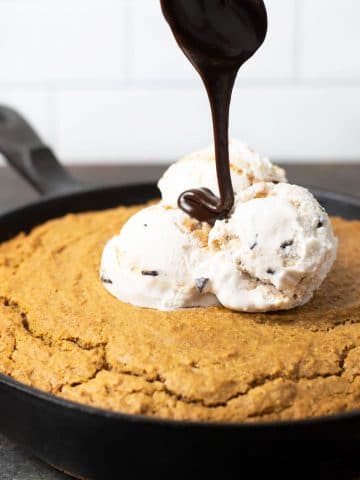 drizzling hot fudge over an ice cream topped skillet cake
