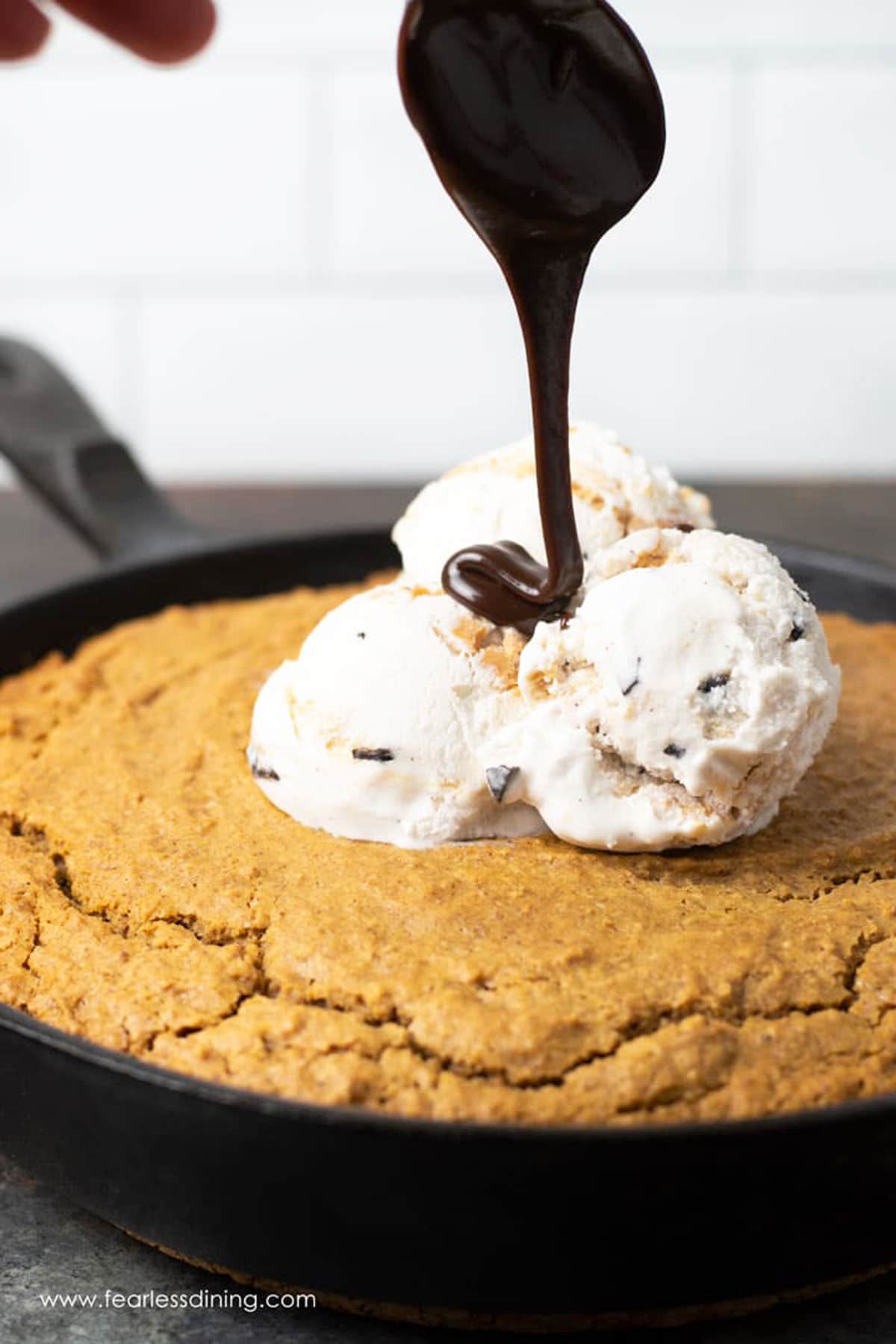 Drizzling hot fudge over an ice cream topped skillet cake.