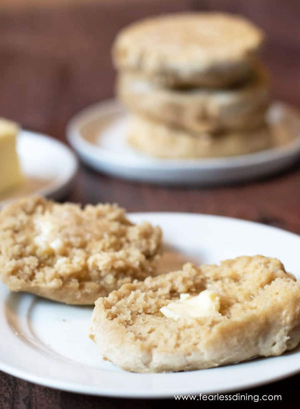 A sliced toasted English muffin on a plate with melted butter on each half.