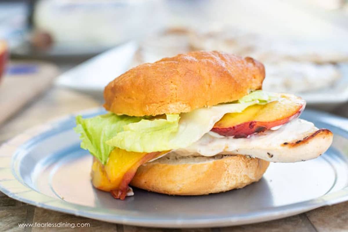 A grilled chicken burger on a paper plate.