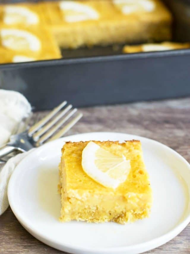 A lemon bar on a small white plate in front of the pan.