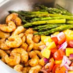 A pan filled with honey garlic shrimp, asparagus, and mango salsa.