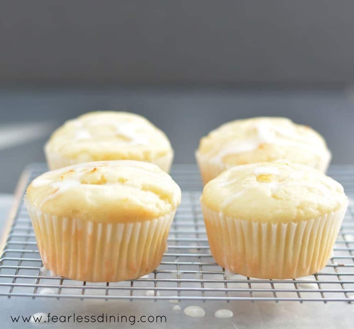 Four lemon cupcakes on a wire rack.