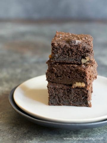 A stack of three brownies on a plate.