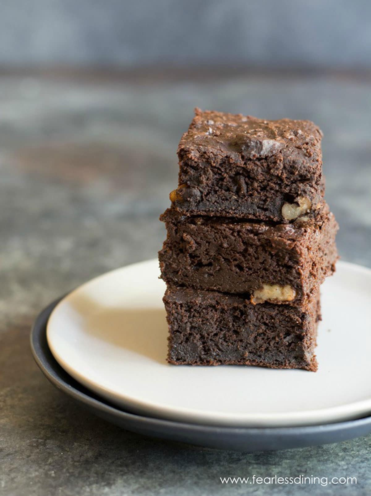 A stack of three paleo brownies on a plate.