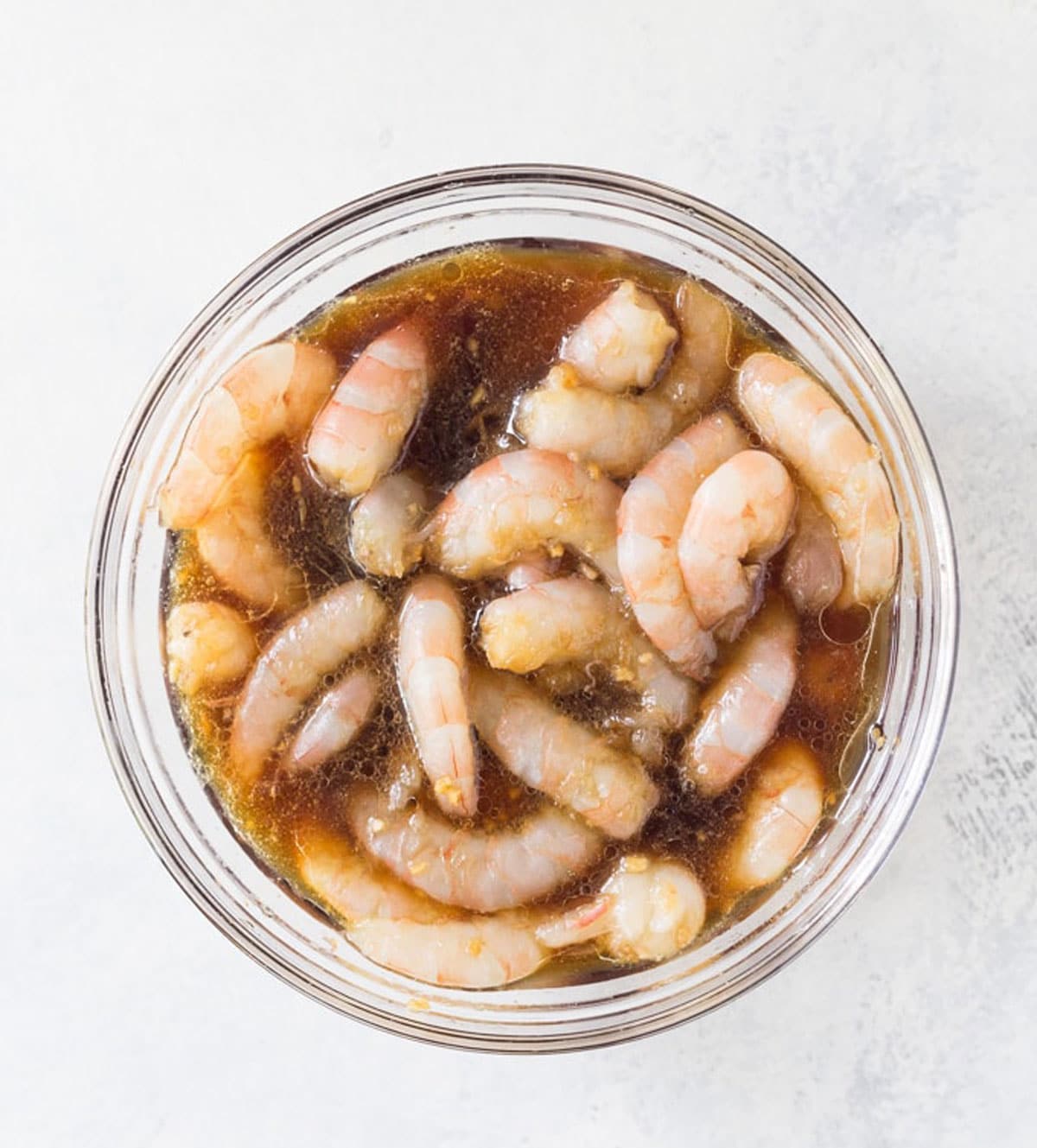 The raw shrimp in a bowl with marinade.