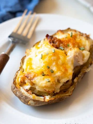 A loaded twice baked potato on a small white plate.