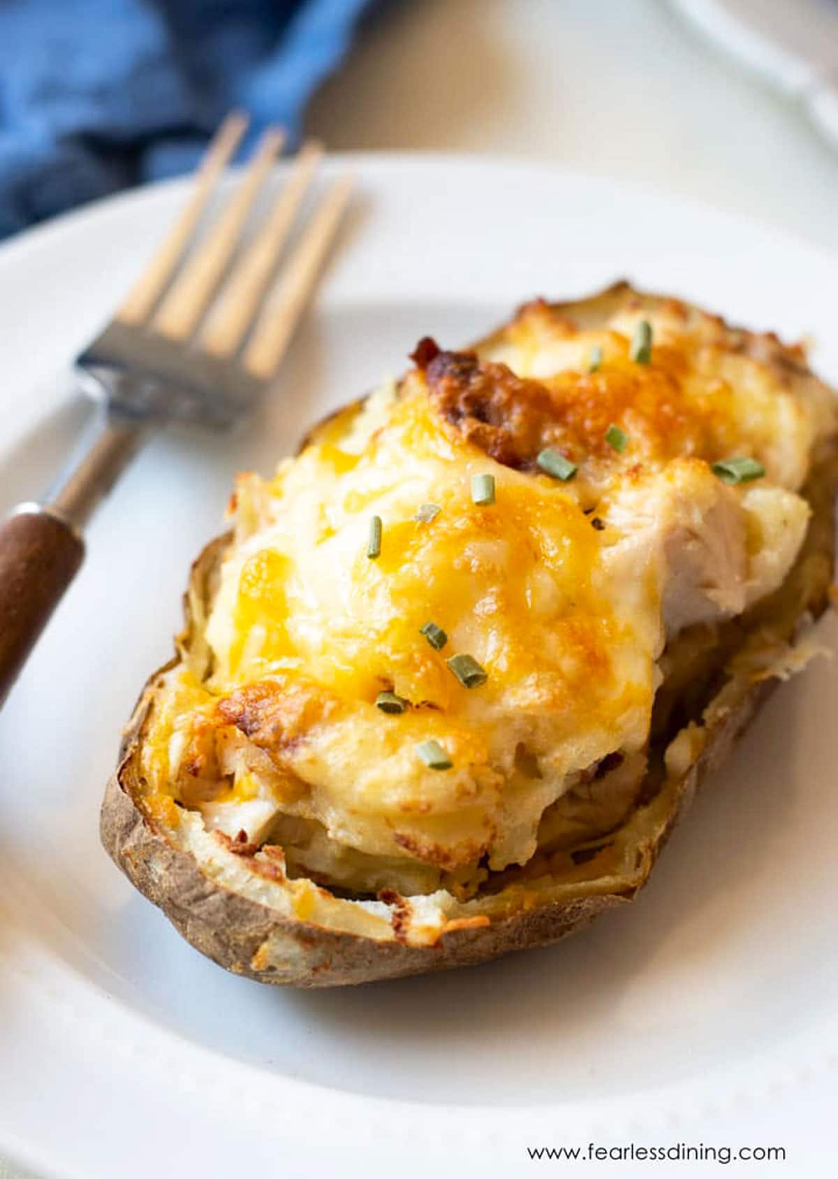 A loaded twice baked potato on a small white plate.