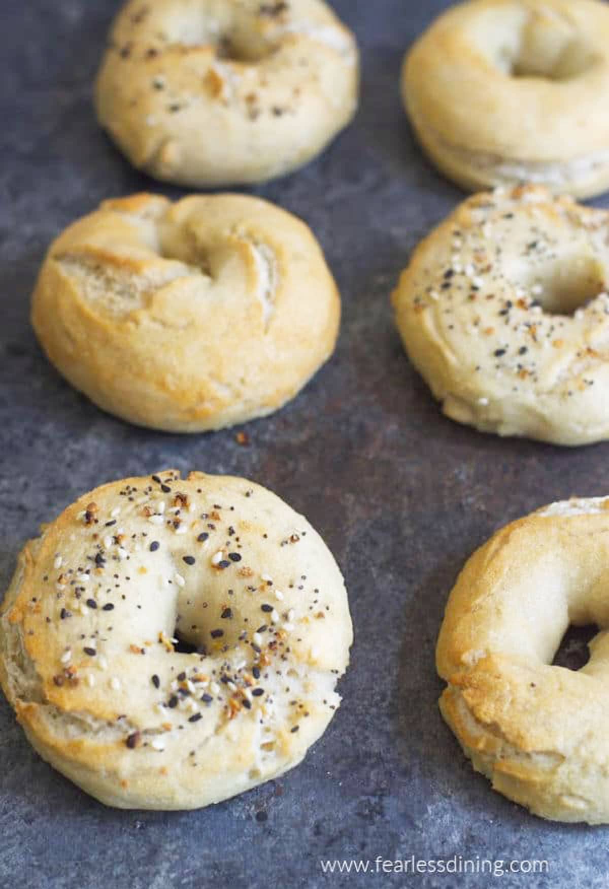 Baked gluten free bagels on a baking sheet.