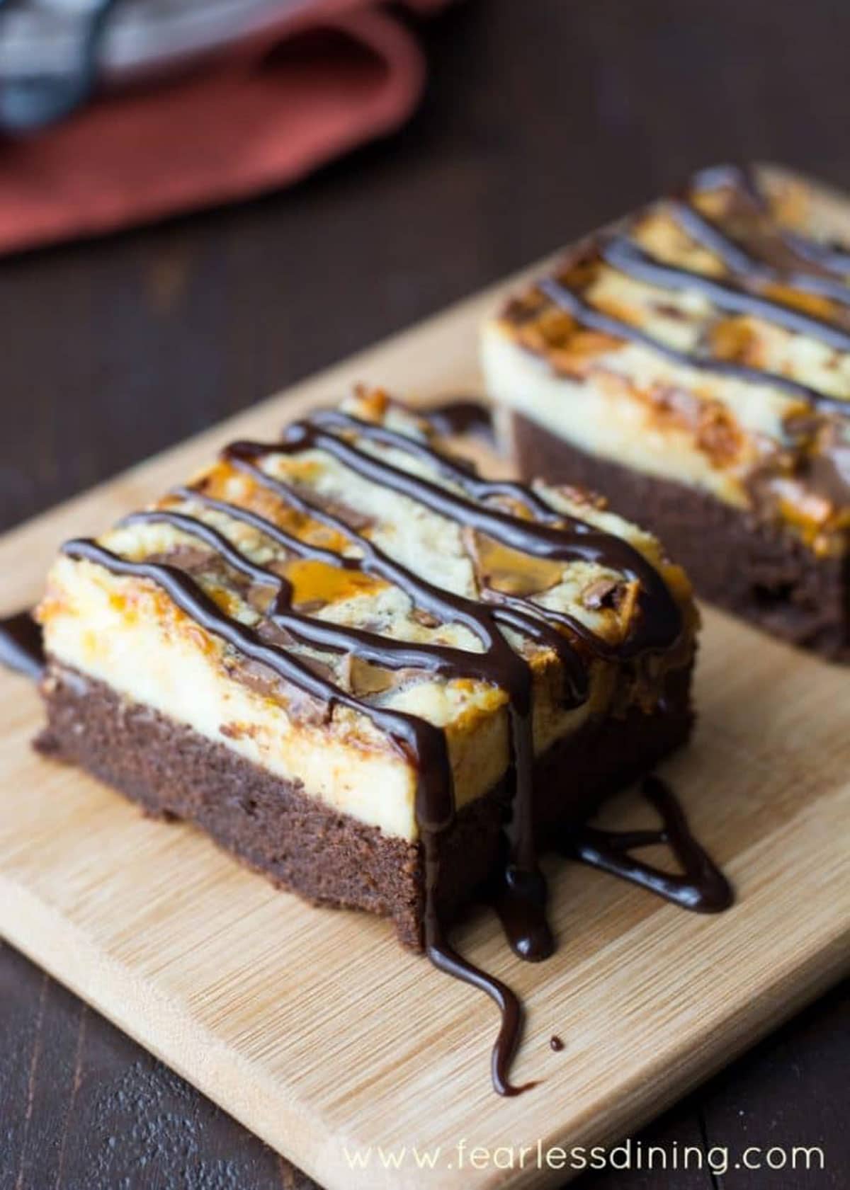 Gluten free cheesecake brownie bars on a wooden tray.