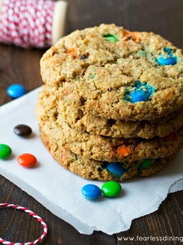 a stack of four large M and M cookies on a napking