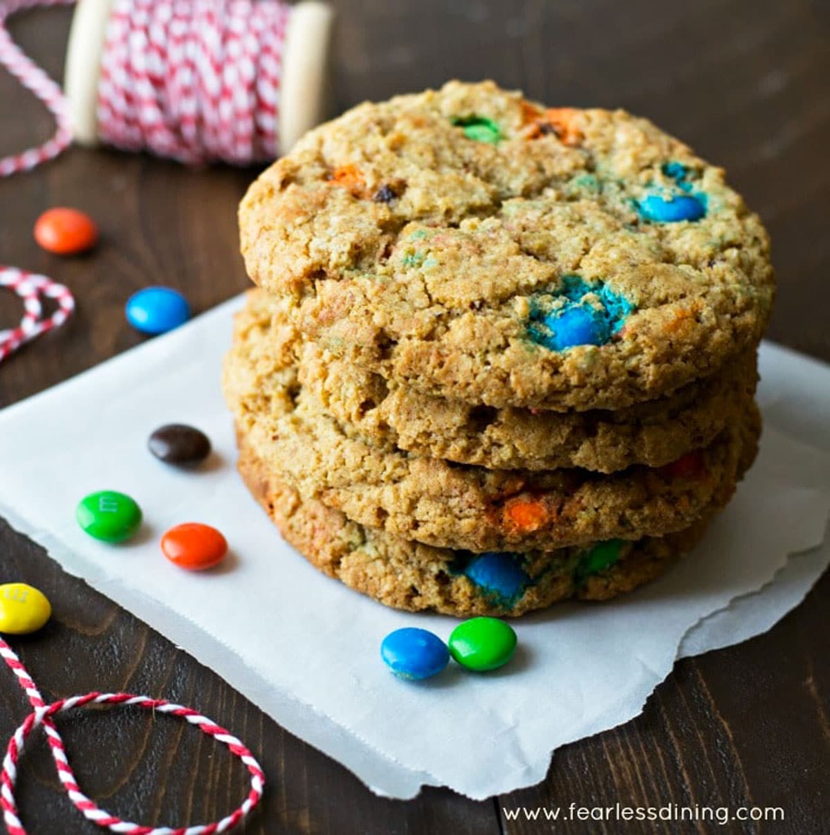 A stack of four large M and M cookies on a napkin.