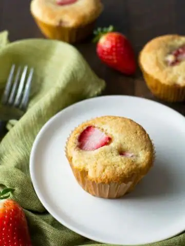 a gluten free strawberry muffin on a plate next to more muffins