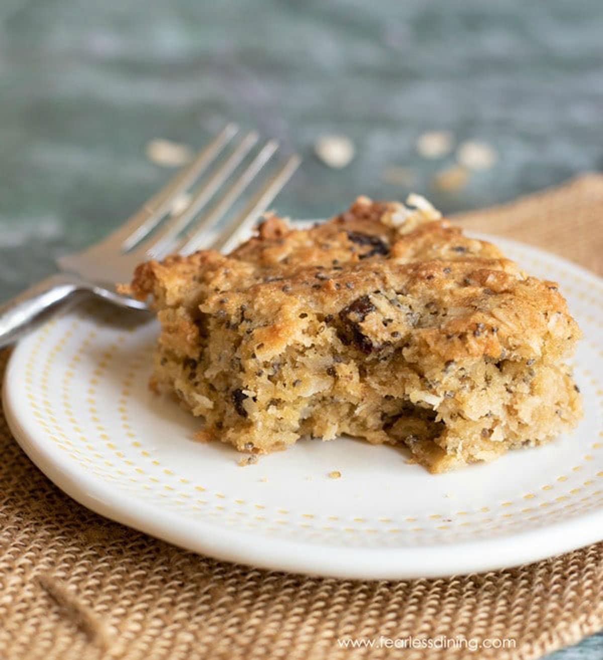 A gluten free breakfast bar on a plate with a piece cut out with a fork.