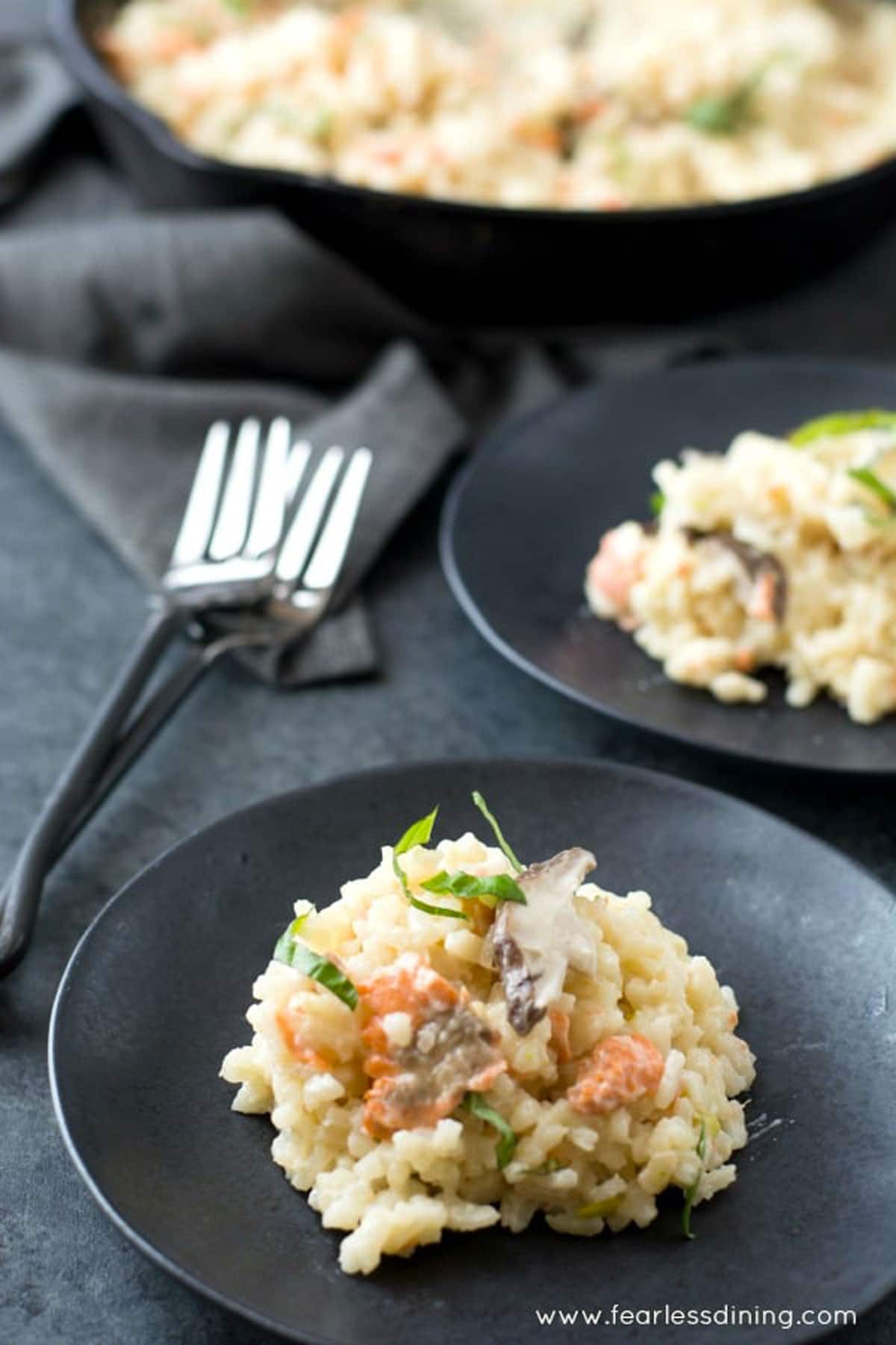 Two black plates with gluten free smoked salmon risotto.