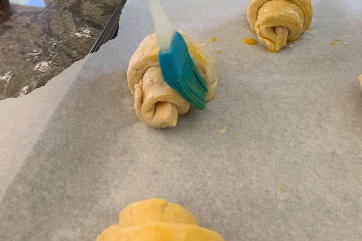 Brushing an egg wash on the crescent roll dough.