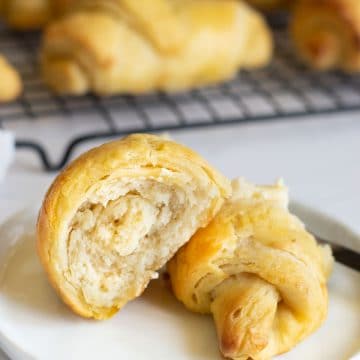 Two halves of a crescent roll on a white plate.
