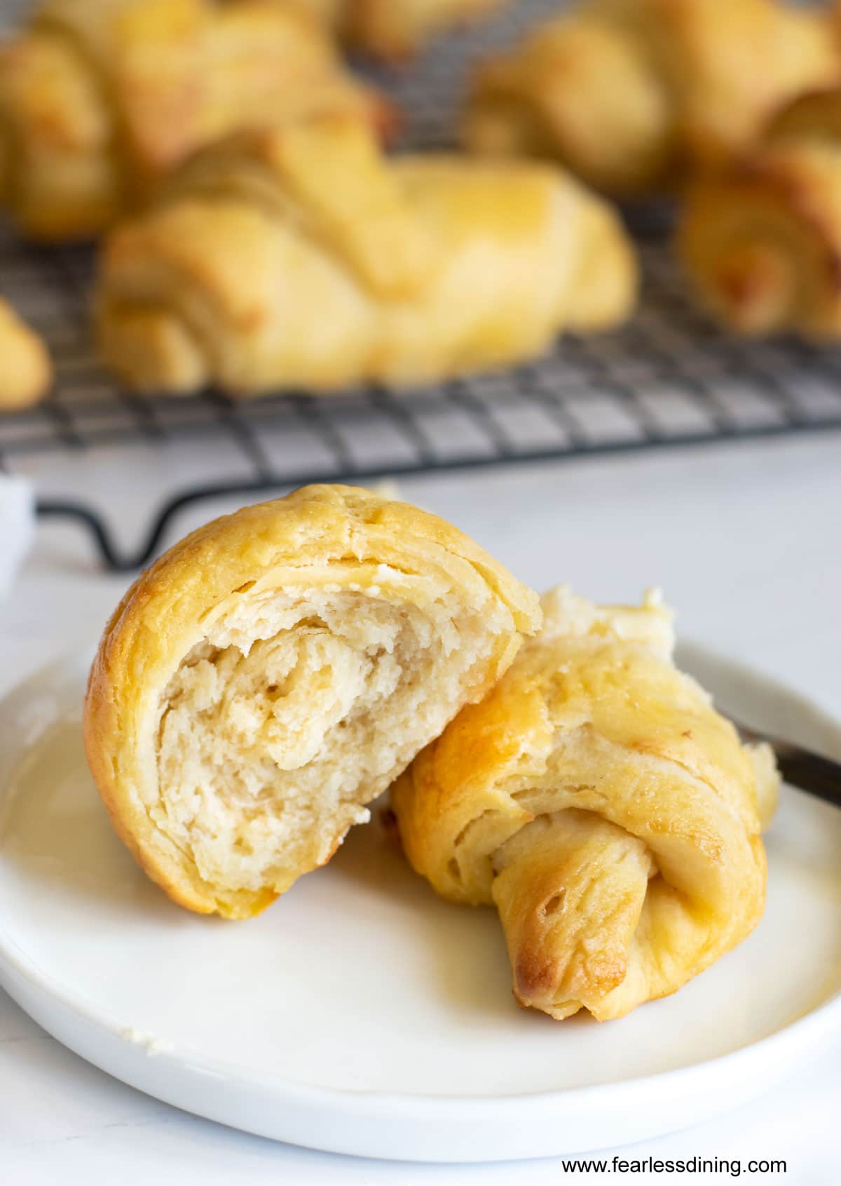 Two halves of a crescent roll on a white plate.