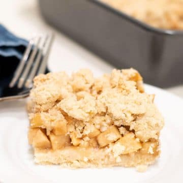A slice of gluten free apple crumble bar on a small white plate.