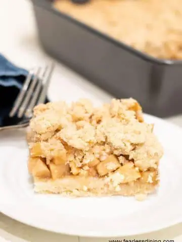 a slice of gluten free apple crumble bar on a small white plate