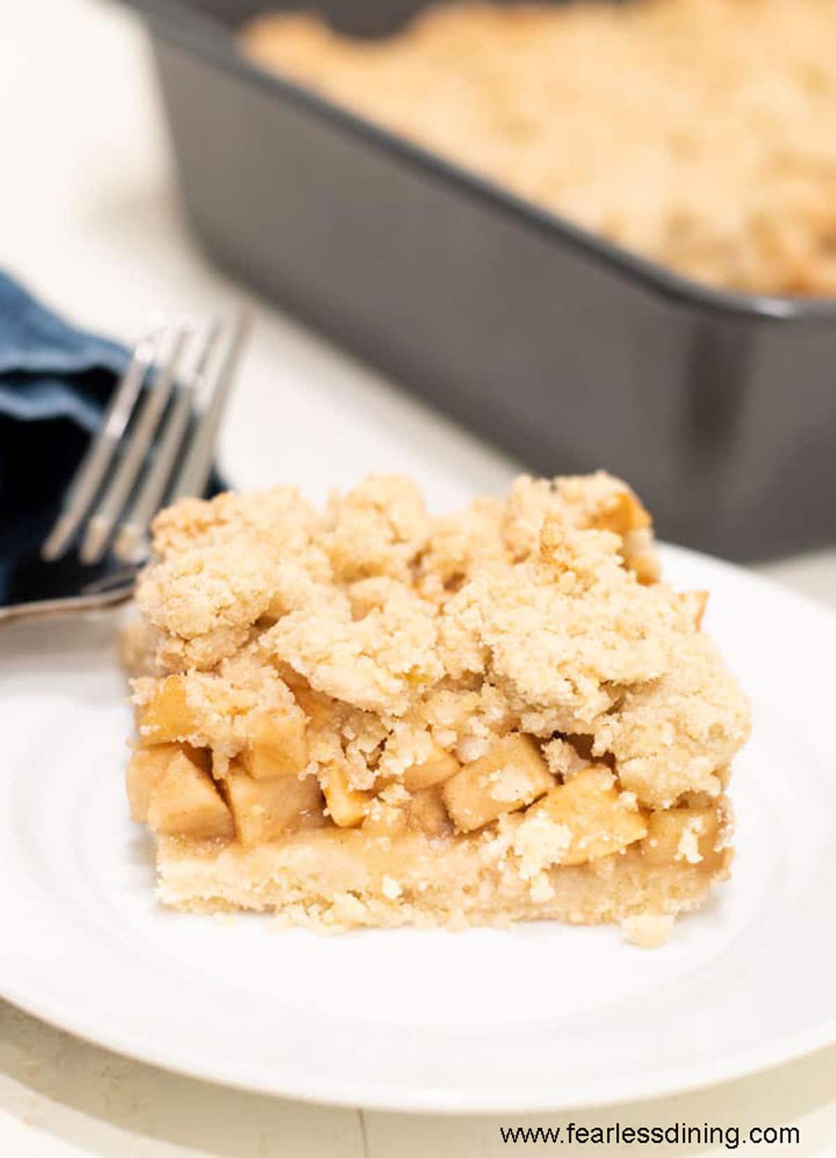 A slice of gluten free apple crumble bar on a small white plate.