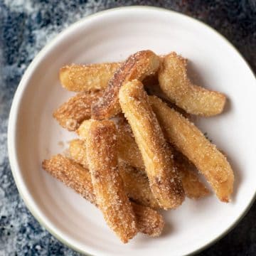 A bowl full of cinnamon sugar coated fried churros.