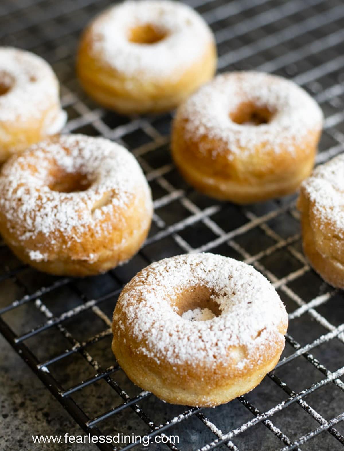 A rack of egg-free donuts with powdered sugar dusted over them.