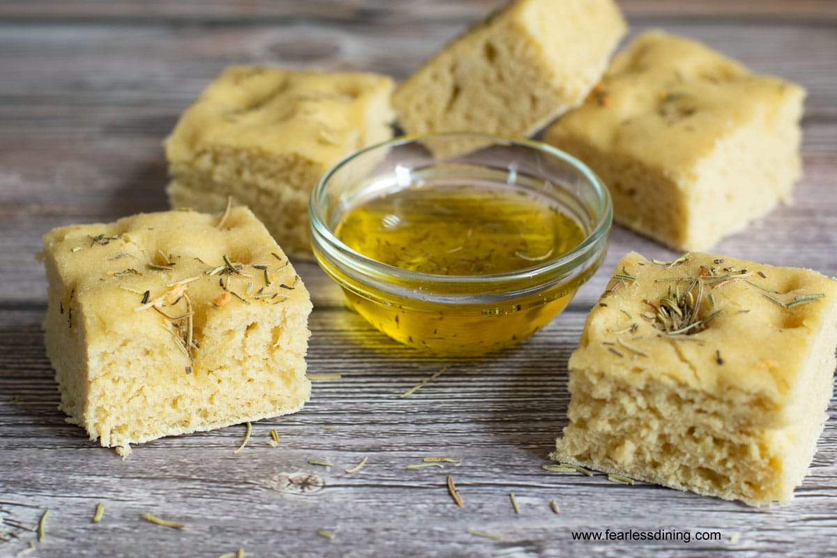 focaccia bread slices around a small glass bowl of herb infused oil 