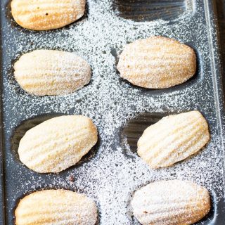 A tray of gluten free madeleines dusted with powdered sugar.