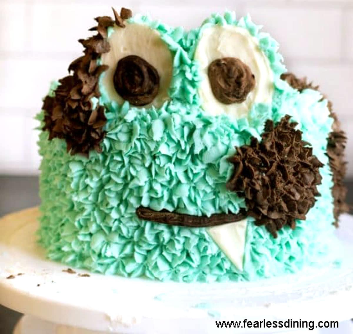 A finished cake decorated like a turquoise monster.