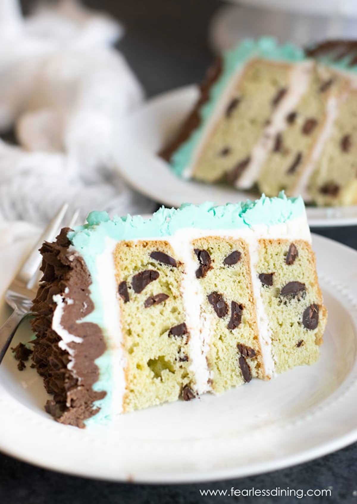 Two slices of mint chocolate chip cake on small white plates.