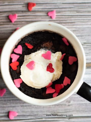a cooked brownie mug with vanilla ice cream and pink and red heart sprinkles